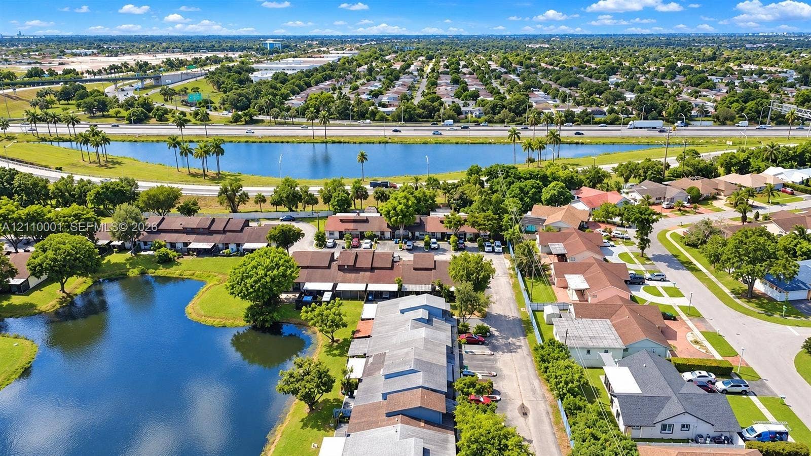 3617 SW 69th Terrace, #24-Z, Miramar, FL 33023 Aerial perspective featuring multi-unit structures, water frontage, landscaped greenery, and paved parking areas
