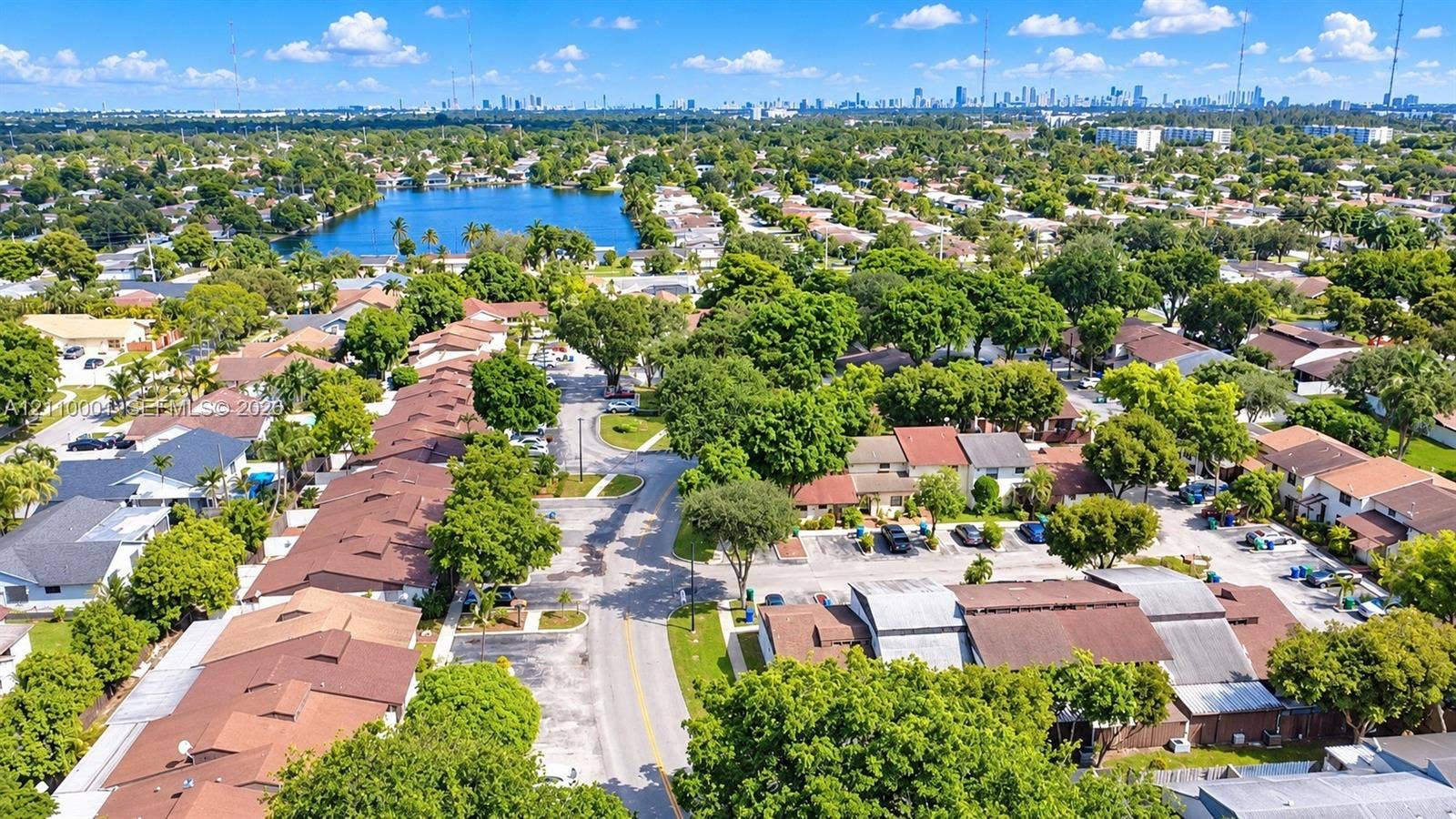3617 SW 69th Terrace, #24-Z, Miramar, FL 33023 Aerial perspective featuring a residential community with mature canopy trees, proximity to a lake, and distant cityscape