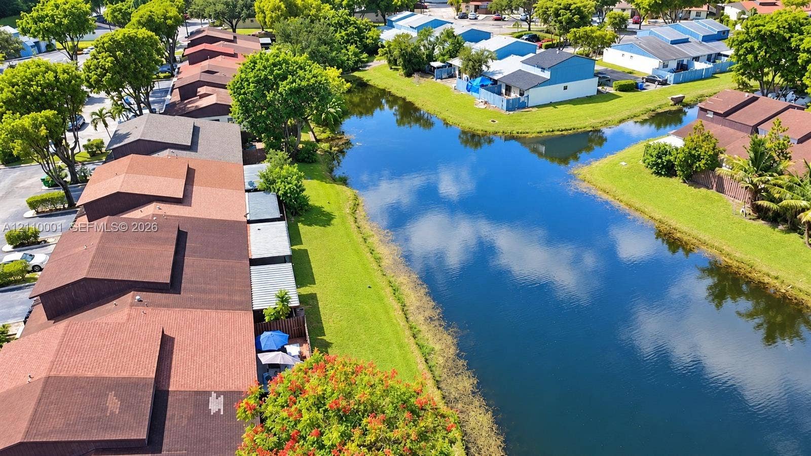 3617 SW 69th Terrace, #24-Z, Miramar, FL 33023 Aerial perspective featuring shingle roofing, residential structures, and a waterway with expansive lawn areas and mature trees