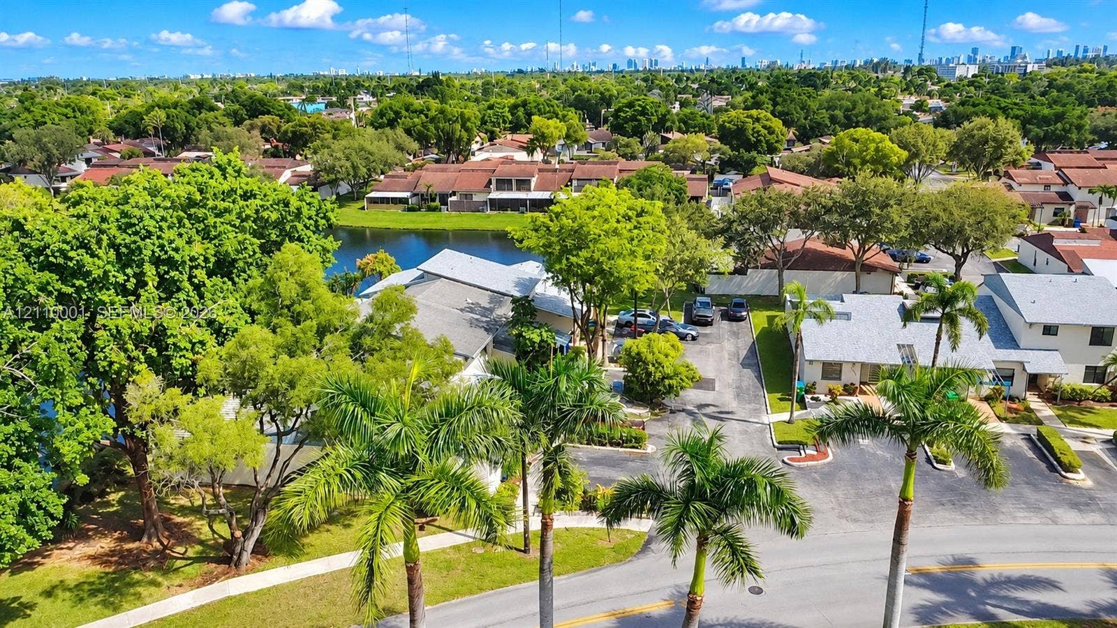 3617 SW 69th Terrace, #24-Z, Miramar, FL 33023 Aerial perspective featuring palm-lined streets, mature trees, a central lake, and multi-unit residential structures
