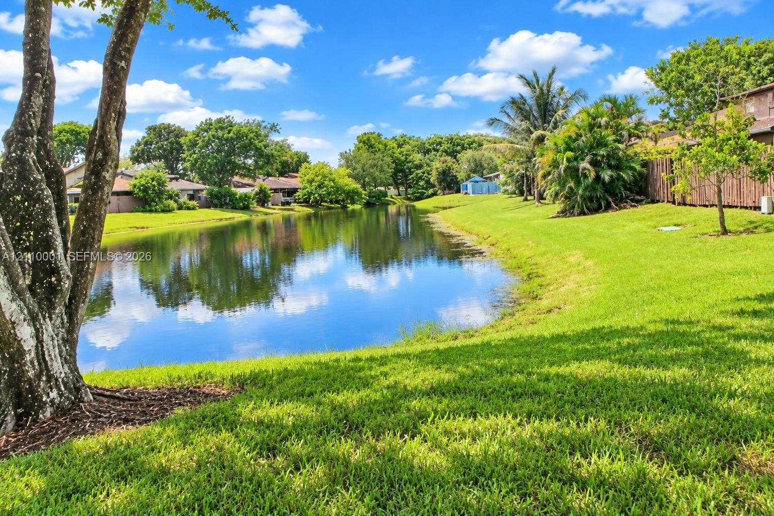 3617 SW 69th Terrace, #24-Z, Miramar, FL 33023 Waterfront lot featuring a grass lawn, mature trees, and wooden fencing