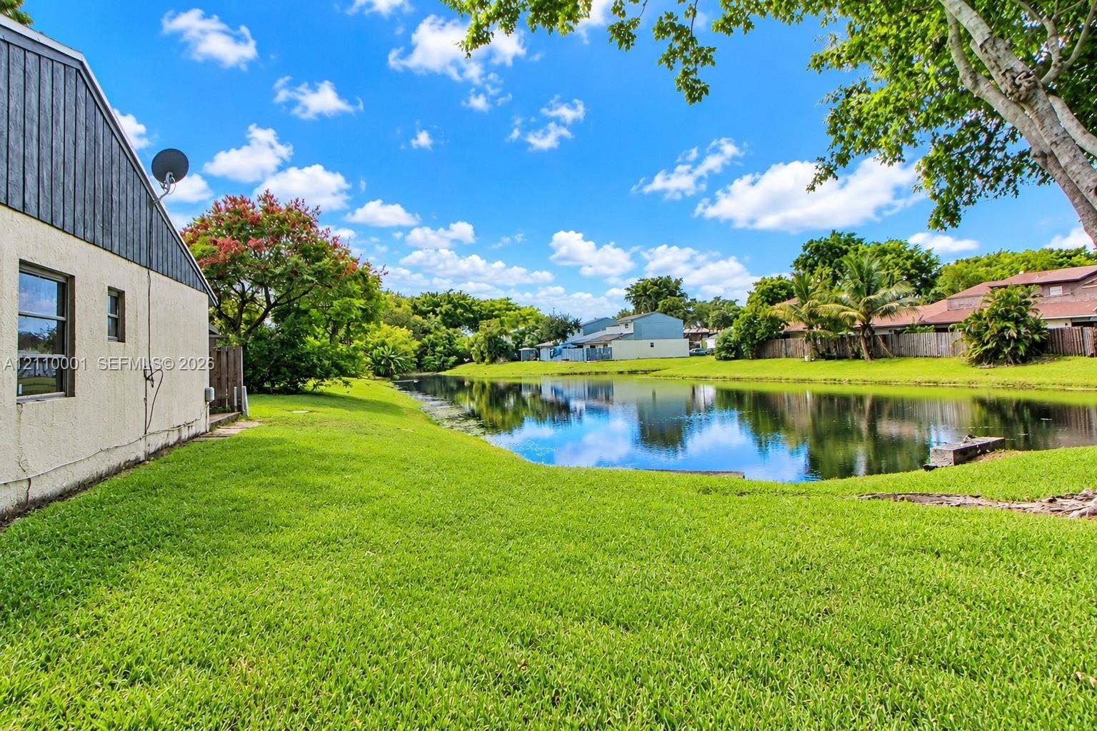 3617 SW 69th Terrace, #24-Z, Miramar, FL 33023 Waterfront backyard featuring a manicured lawn, perimeter wood fencing, and mature landscaping