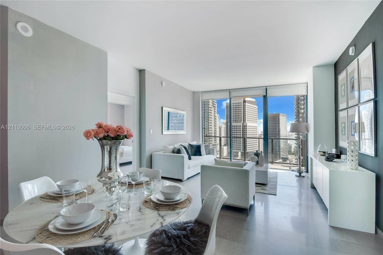 Floor-to-ceiling windows, polished concrete flooring, neutral wall palette, and expansive urban skyline backdrop