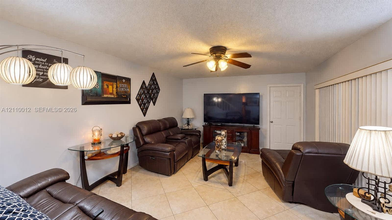 1601 16th Terrace, Palm Beach Gardens, FL 33418 Living area featuring diagonal-set tile flooring, a central ceiling fan with integrated lighting, and vertical window blinds