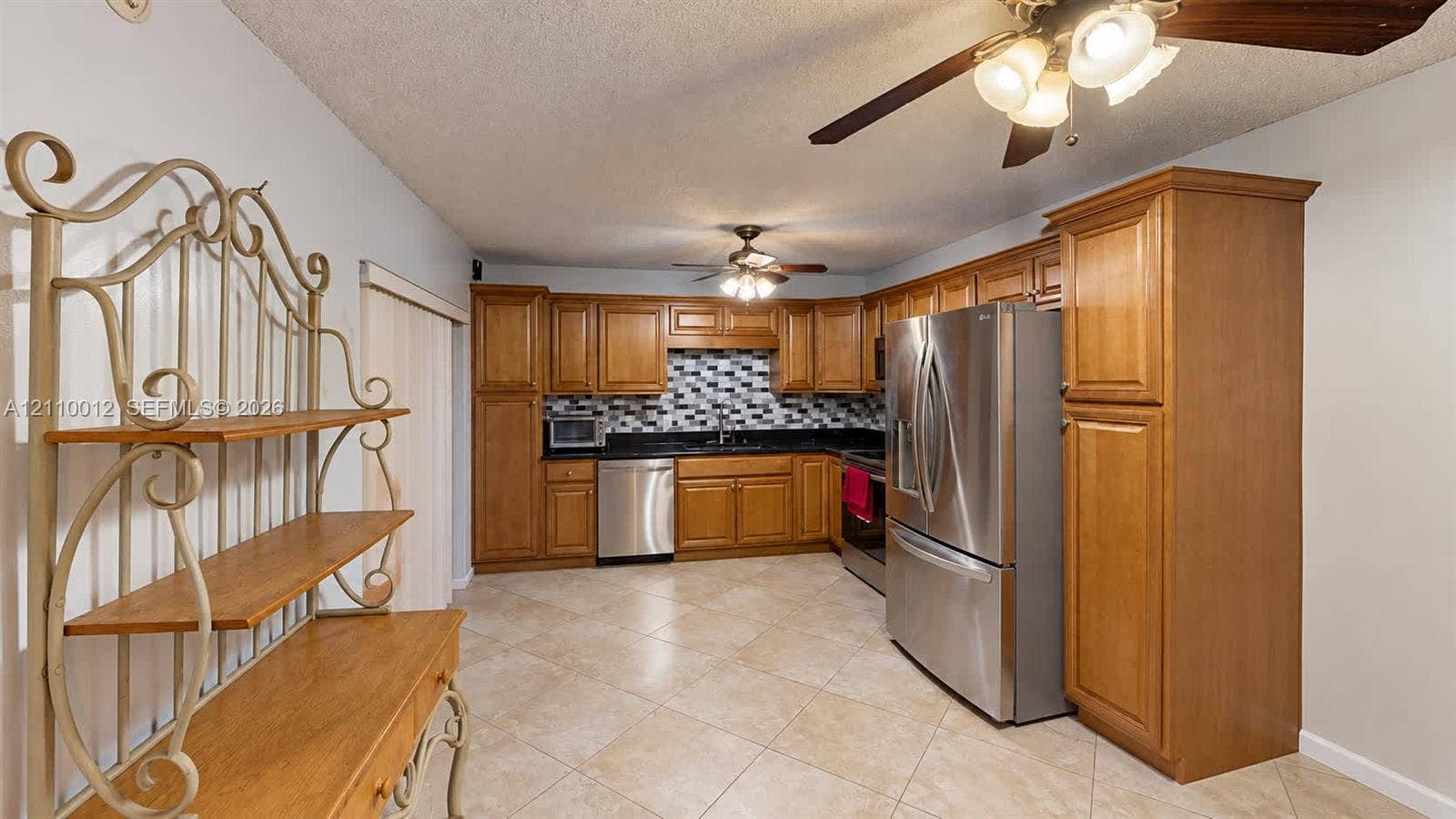1601 16th Terrace, Palm Beach Gardens, FL 33418 Kitchen featuring wooden cabinetry, dark countertops, a mosaic tile backsplash, stainless steel appliances, and ceramic tile flooring
