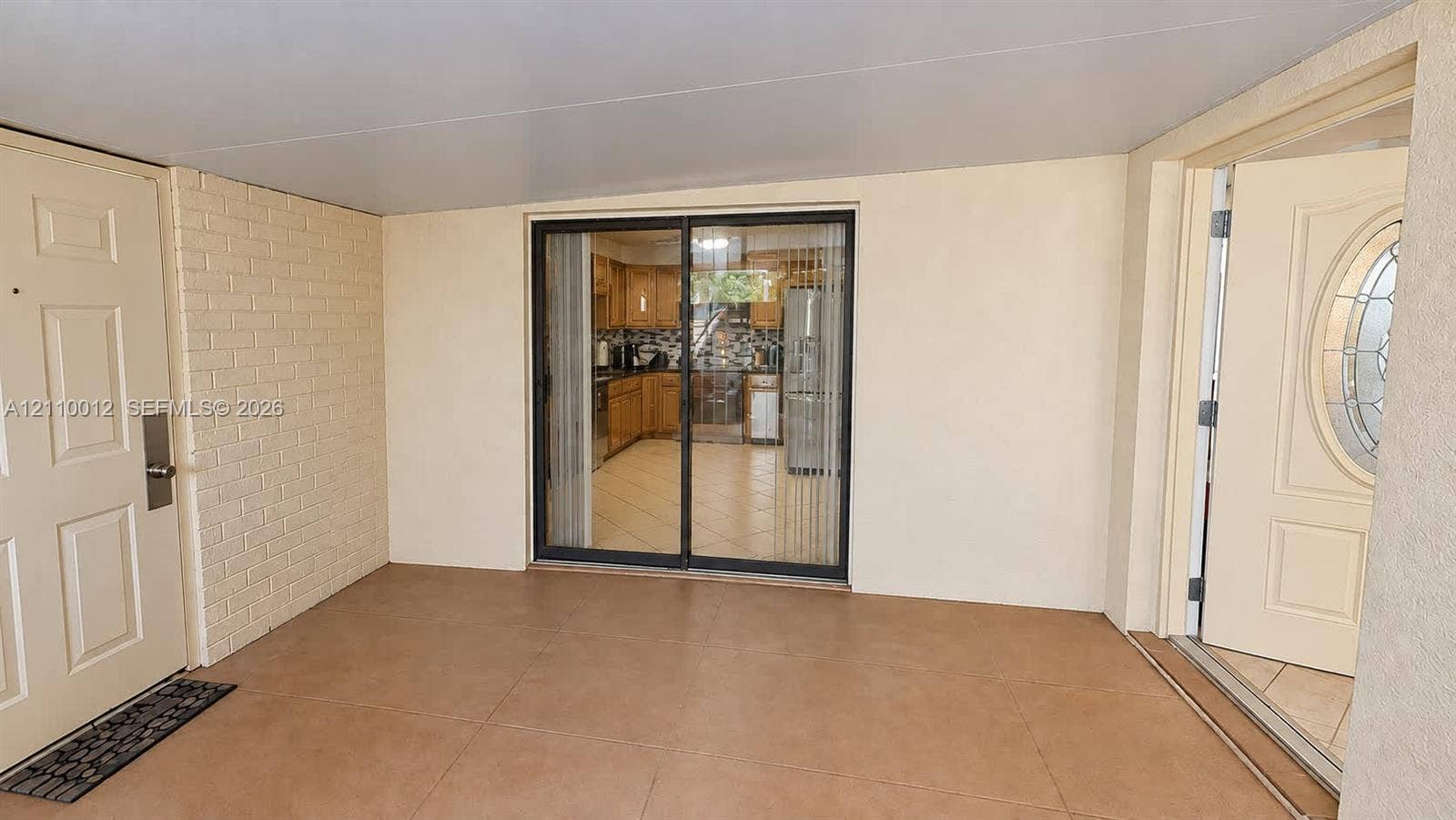 1601 16th Terrace, Palm Beach Gardens, FL 33418 Covered patio featuring ceramic tile flooring, a painted brick accent wall, and sliding glass door entry