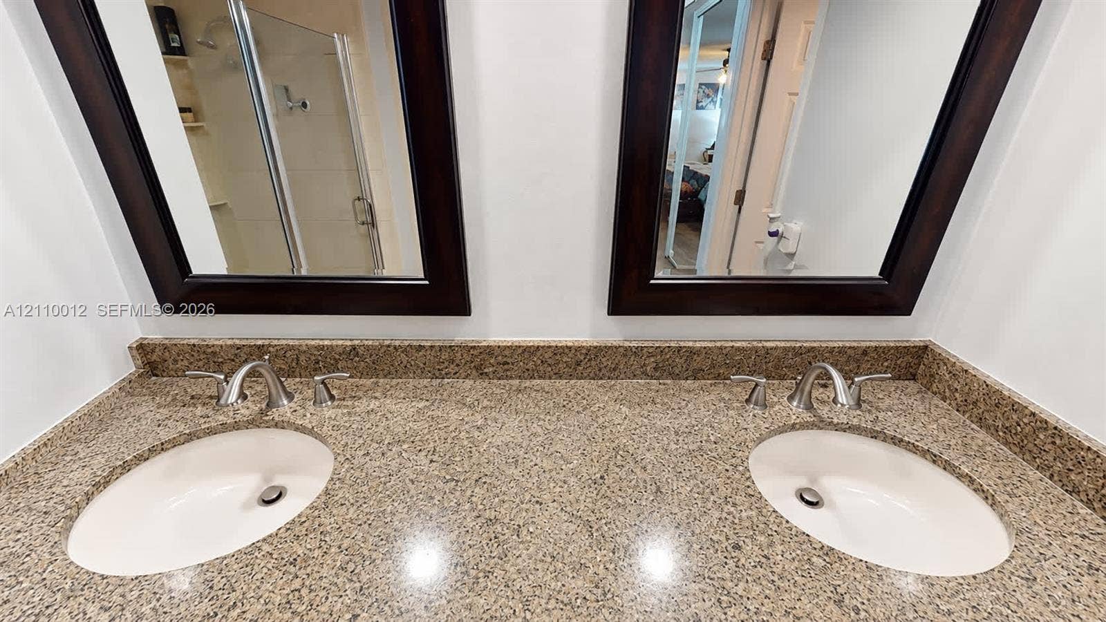 1601 16th Terrace, Palm Beach Gardens, FL 33418 Double vanity featuring stone countertops, dual undermount sinks, polished chrome widespread faucets, and two dark-finished framed wall mirrors