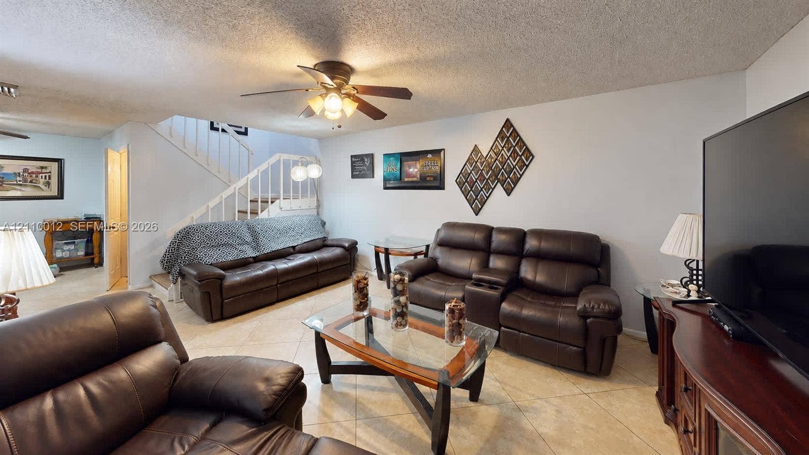 1601 16th Terrace, Palm Beach Gardens, FL 33418 Living area featuring large-format tile flooring, a ceiling fan with integrated lighting, and a white staircase with a metal railing