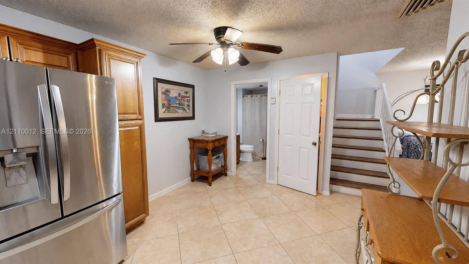 1601 16th Terrace, Palm Beach Gardens, FL 33418 Kitchen area featuring a stainless steel refrigerator, wood cabinetry, ceiling fan, and tile flooring