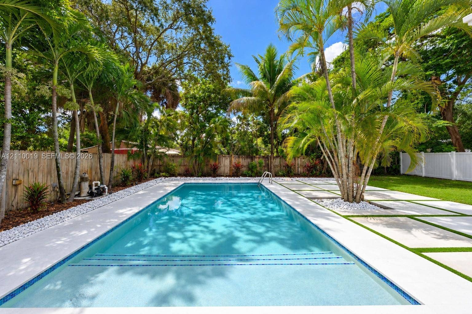1708 SW 11th Street, Fort Lauderdale, Fort Lauderdale, FL 33312 In-ground swimming pool with built-in stairs, bordered by a concrete paver patio with turf inlay, white river rock accents, and mature palm trees