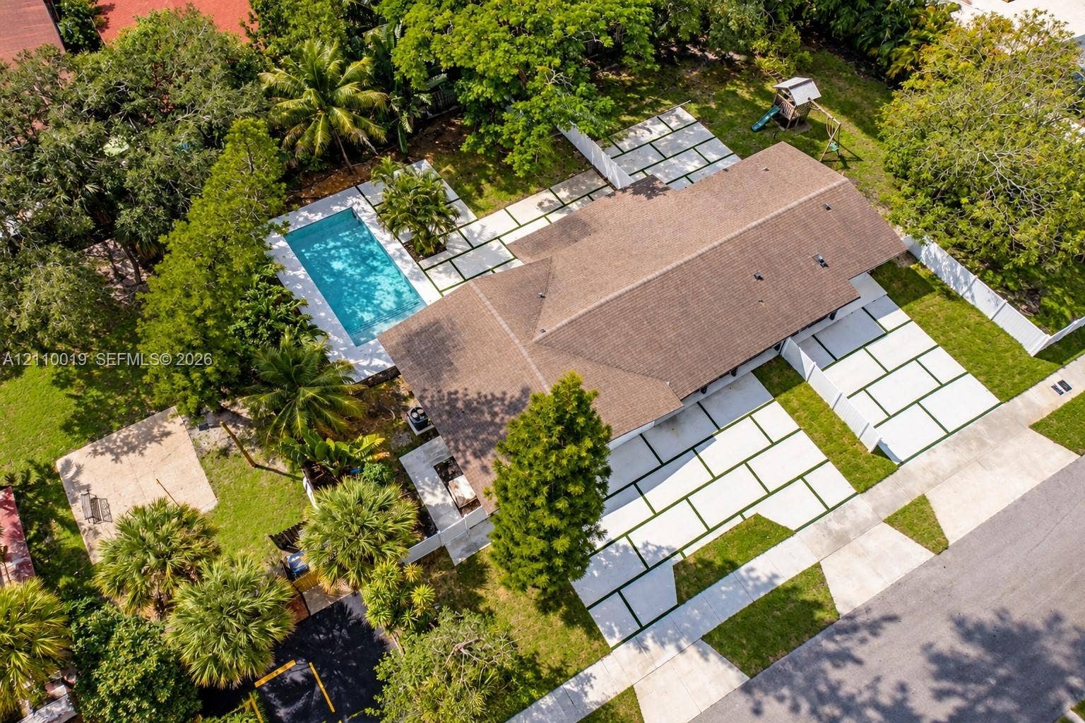 1708 SW 11th Street, Fort Lauderdale, Fort Lauderdale, FL 33312 Aerial perspective of a property featuring an in-ground swimming pool, extensive paver hardscaping with geometric inlay, mature landscape, and a fenced perimeter