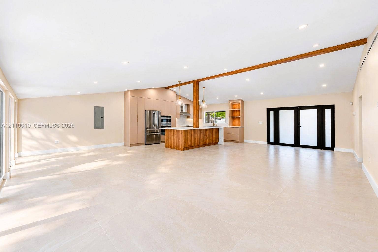 1708 SW 11th Street, Fort Lauderdale, Fort Lauderdale, FL 33312 Expansive open-concept interior featuring vaulted ceilings, large-format tile flooring, a wood-accented center island, built-in cabinetry, and black-framed multi-panel glass doors