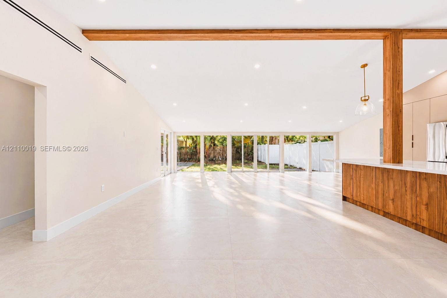 1708 SW 11th Street, Fort Lauderdale, Fort Lauderdale, FL 33312 Open-concept interior featuring large-format tile flooring, exposed wood ceiling beams, floor-to-ceiling glass panel windows, and a wood-finish kitchen island with a white countertop