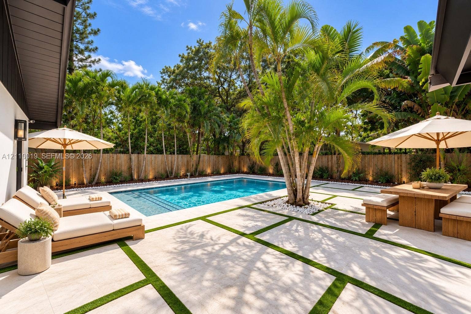 1708 SW 11th Street, Fort Lauderdale, Fort Lauderdale, FL 33312 In-ground swimming pool with steps, surrounded by light-toned rectangular stone pavers and synthetic turf inlay, enclosed by a wood-slat perimeter fence and mature palm trees
