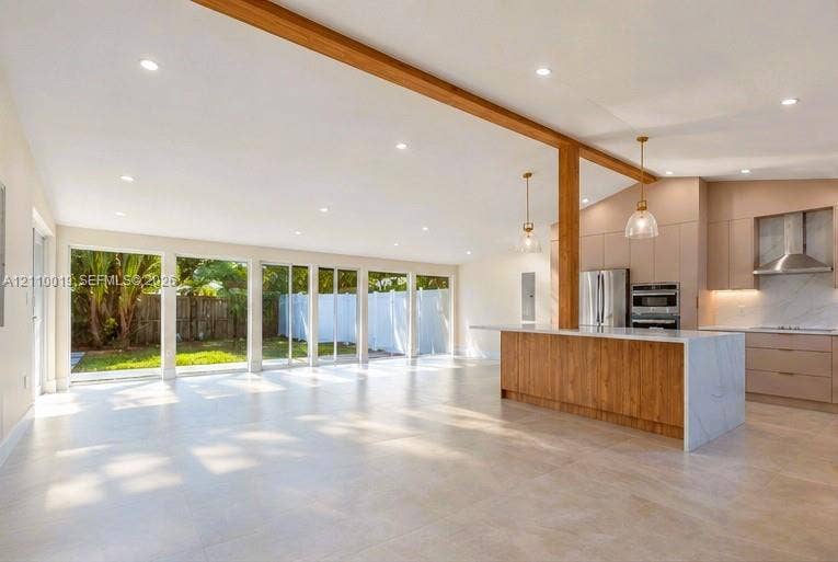 1708 SW 11th Street, Fort Lauderdale, Fort Lauderdale, FL 33312 Open-concept space featuring an exposed wood structural beam, floor-to-ceiling sliding glass doors, a large kitchen island with stone-finish waterfall edges, flat-panel cabinetry, and recessed lighting