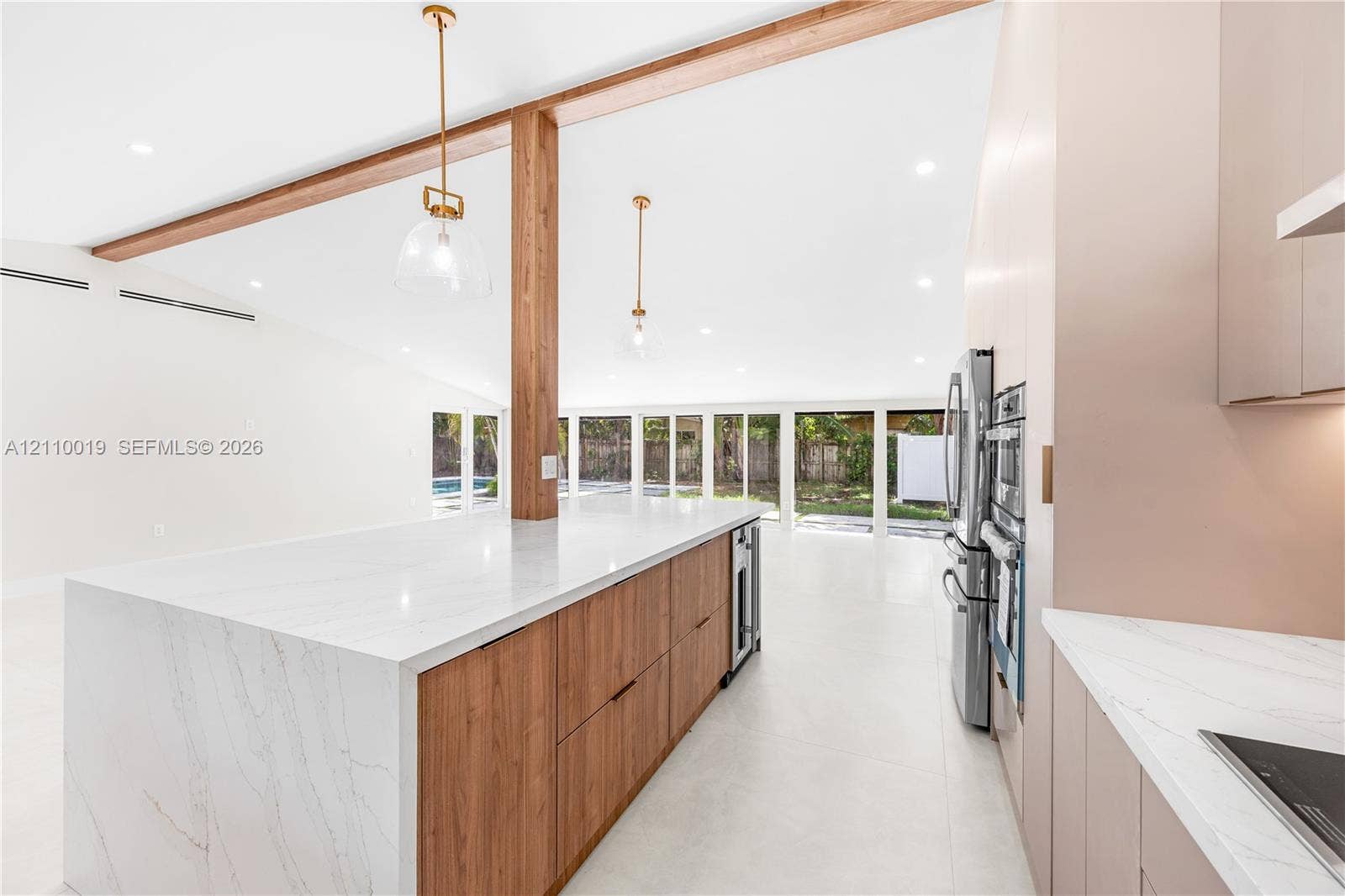 1708 SW 11th Street, Fort Lauderdale, Fort Lauderdale, FL 33312 Kitchen featuring a waterfall-edge stone countertop, wood-finish cabinetry, exposed wood ceiling beams, pendant lighting, and stainless steel built-in appliances