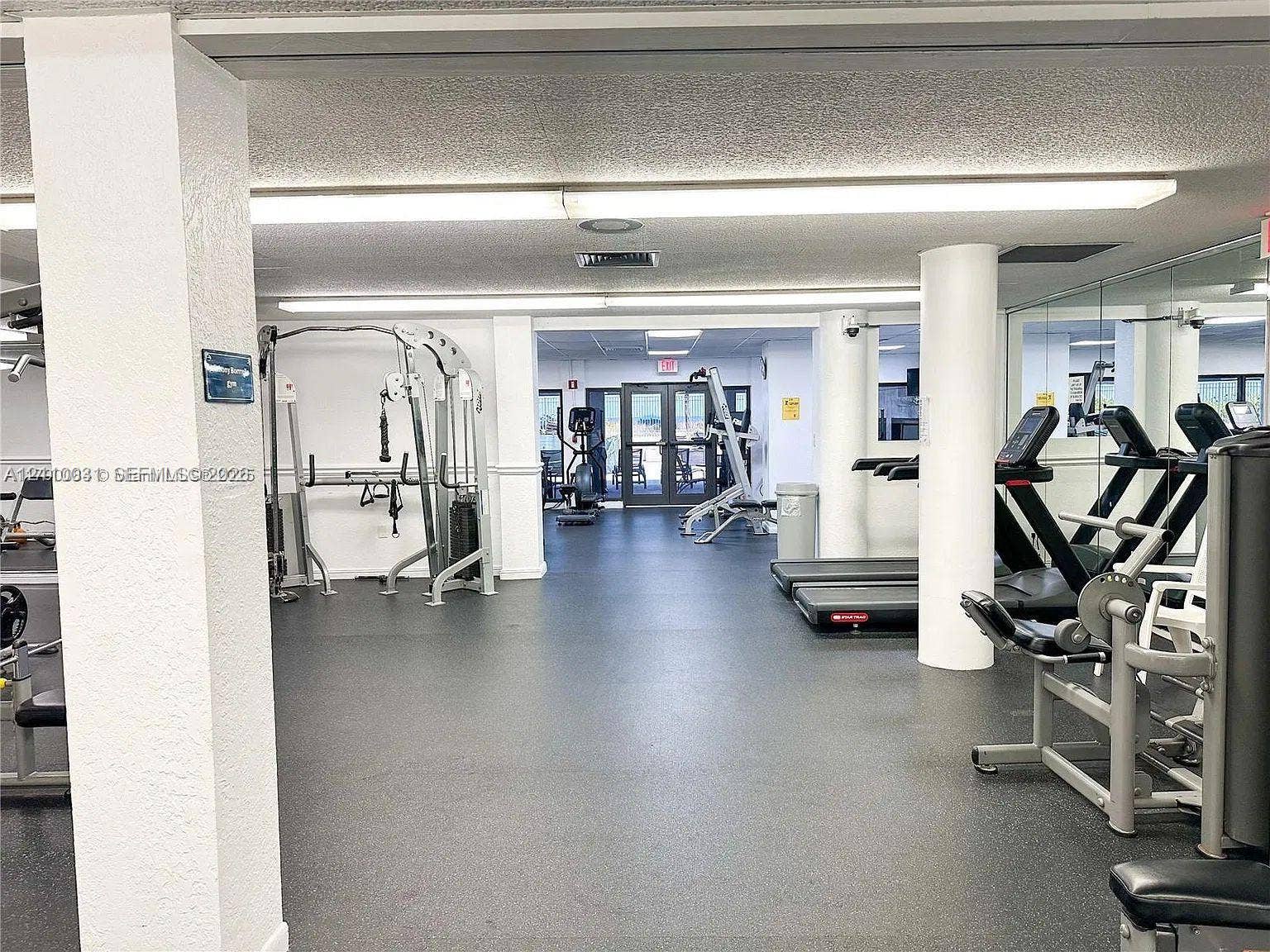 Fitness center featuring rubber flooring, recessed lighting, structural support columns, and mirrored wall panels