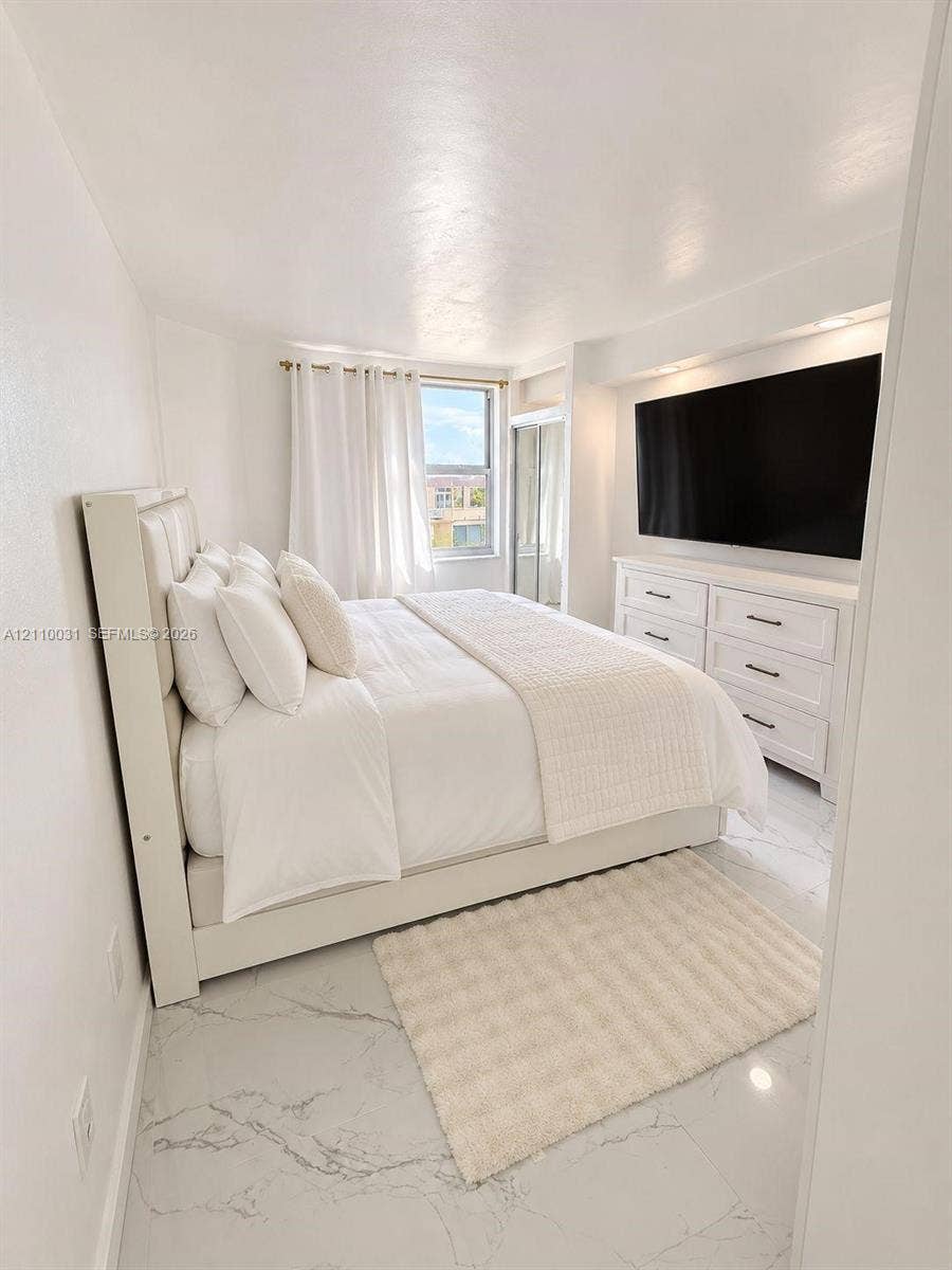 Large-format white tile flooring with grey veining, recessed lighting, and a floor-to-ceiling mirrored closet door