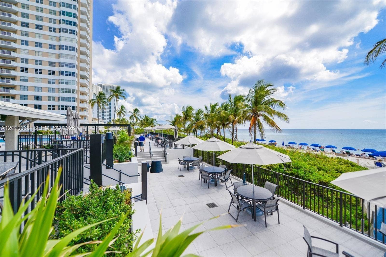 Outdoor terrace featuring tile flooring, metal railings, integrated landscaping, and oceanfront proximity