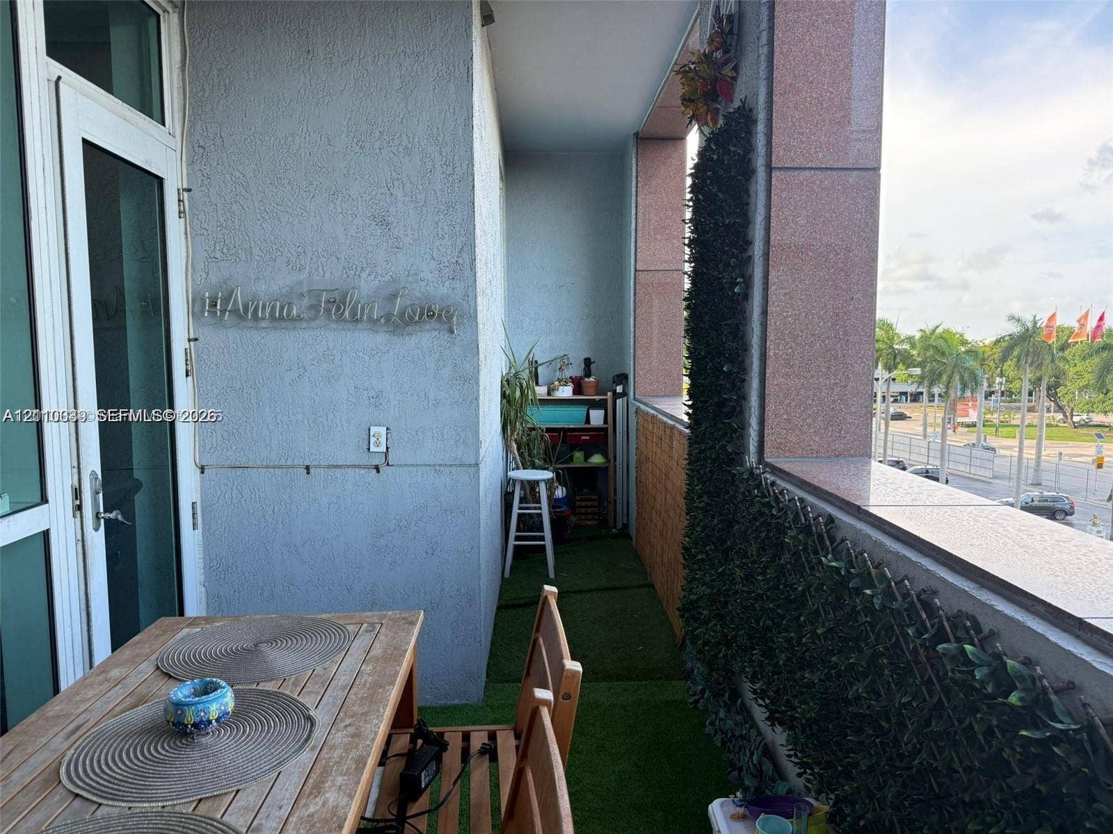 244 Biscayne Boulevard, #301, Miami, FL 33132 Covered balcony featuring textured stucco walls, polished stone-finish railing, and green synthetic turf flooring