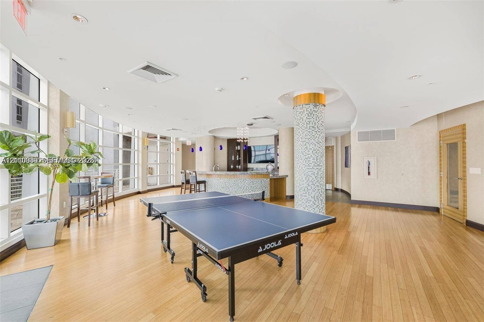 244 Biscayne Boulevard, #301, Miami, FL 33132 Recreational area featuring wood-finish flooring, floor-to-ceiling windows, a mosaic-tiled structural column, and a built-in wet bar with cabinetry