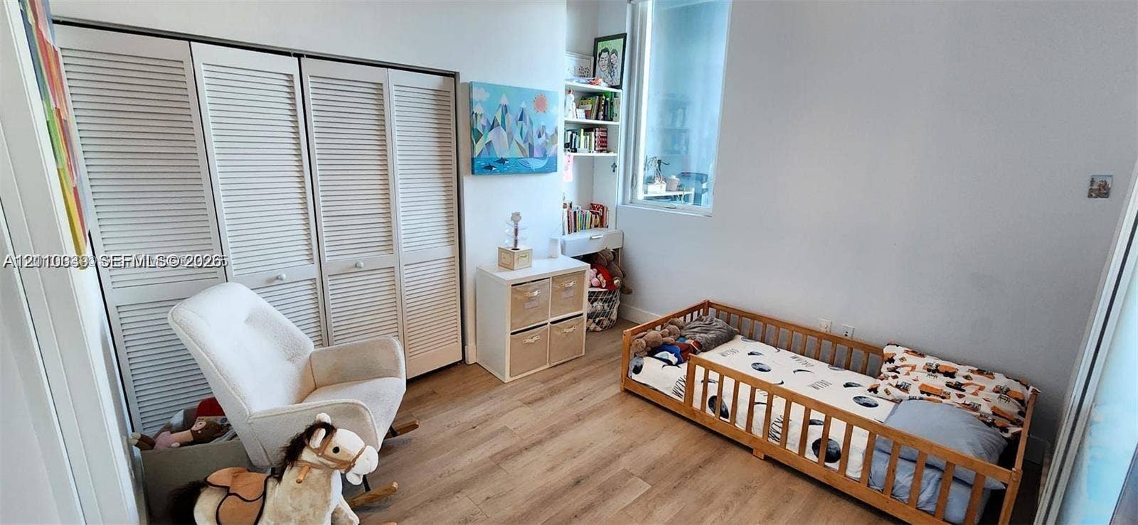 244 Biscayne Boulevard, #301, Miami, FL 33132 Interior room featuring light-toned wood-finish flooring, floor-to-ceiling louvered-panel closet doors, and a built-in white shelving unit