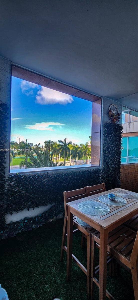 244 Biscayne Boulevard, #301, Miami, FL 33132 Covered balcony featuring artificial turf flooring, accent walls adorned with greenery, and a large fixed-pane window with exterior landscape imagery