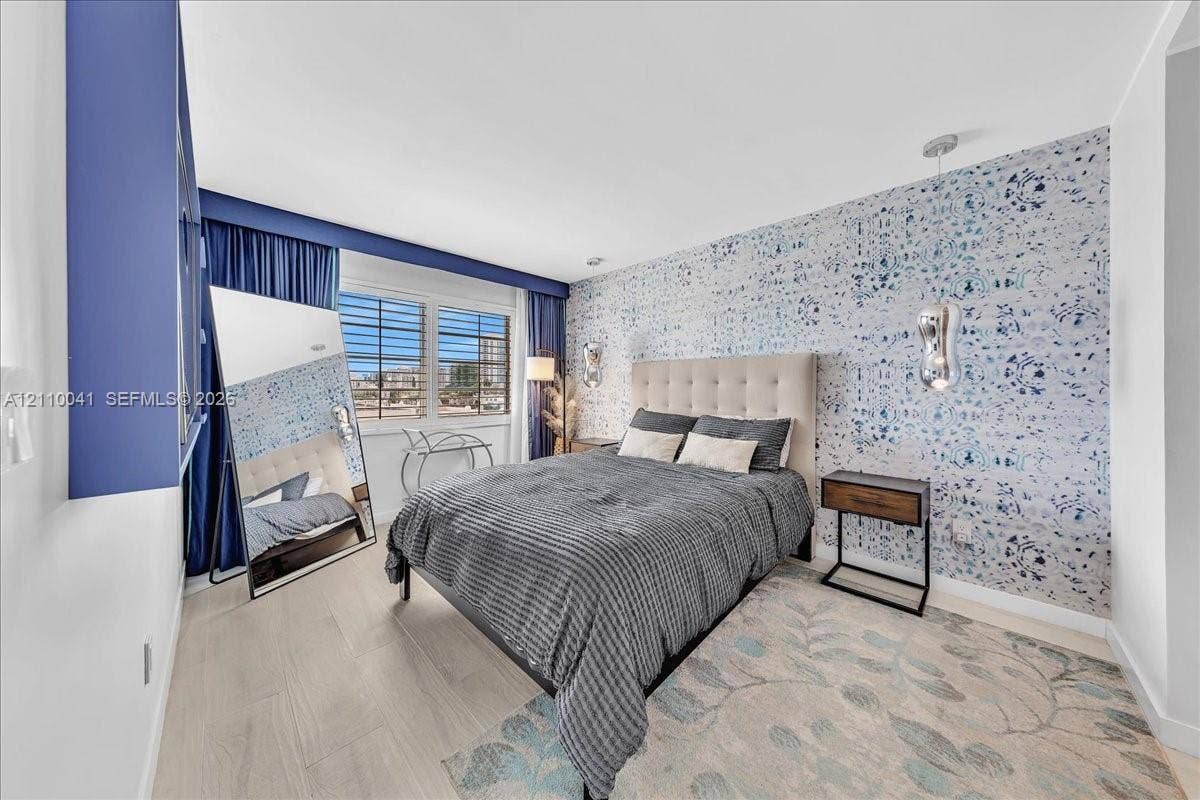 1610 Lenox Avenue, #516, Miami Beach, FL 33139 Bedroom featuring wood-finish flooring, decorative patterned wall covering, recessed ceiling lighting, and suspended metallic pendant light fixtures
