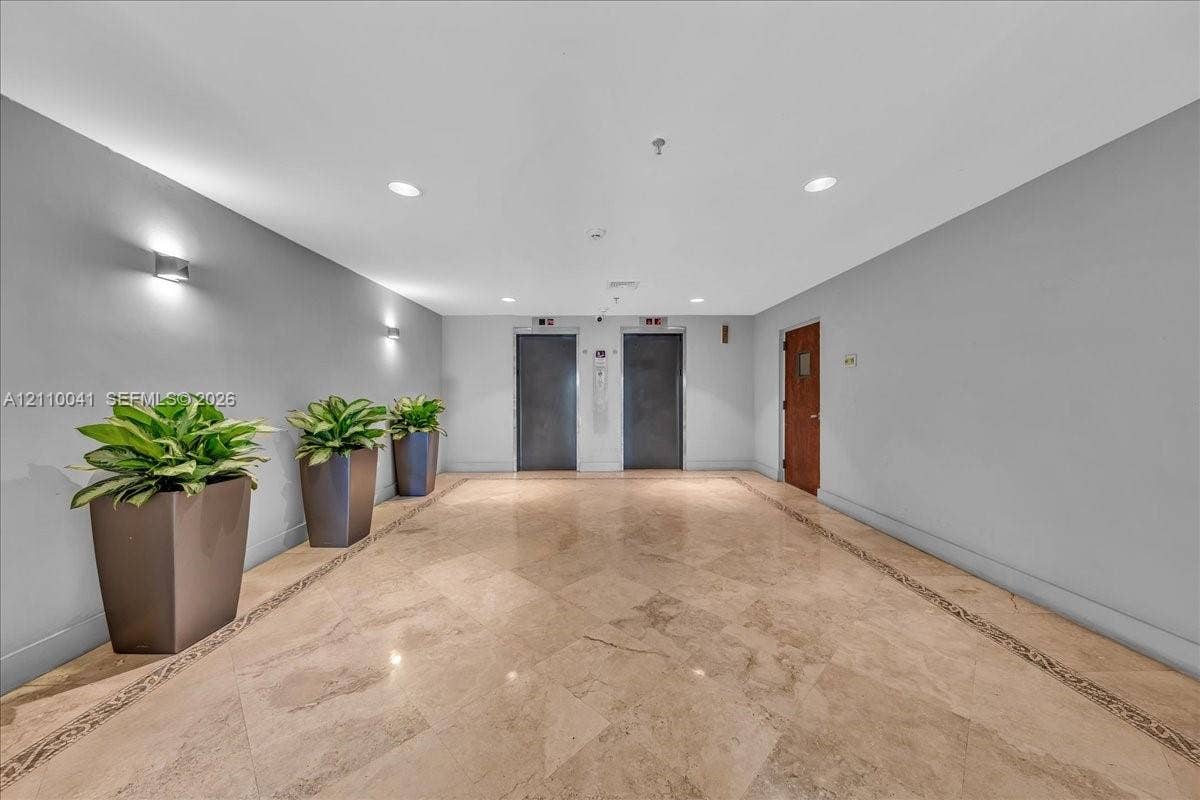 1610 Lenox Avenue, #516, Miami Beach, FL 33139 Common area lobby featuring polished stone flooring with decorative inlay, dual elevator banks, and recessed ceiling lighting