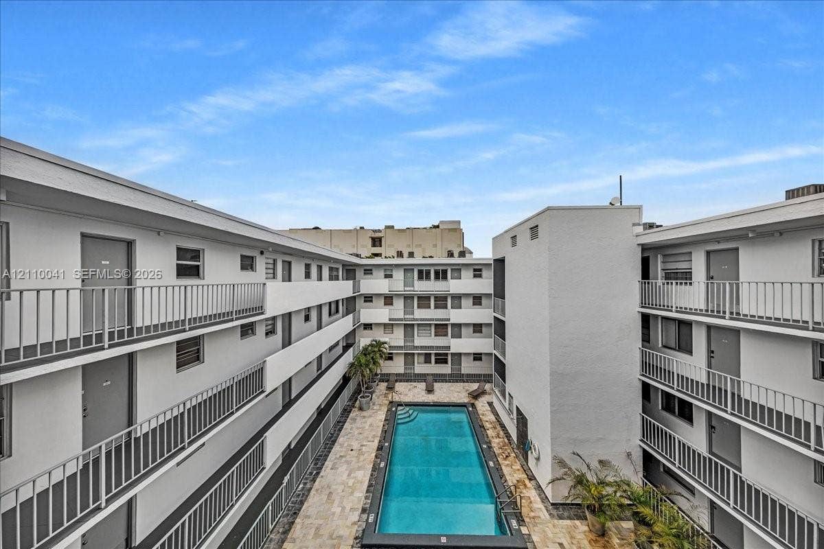 1610 Lenox Avenue, #516, Miami Beach, FL 33139 Rectangular swimming pool featuring a stone-paver deck and surrounding multi-story building exterior with metal balcony railings