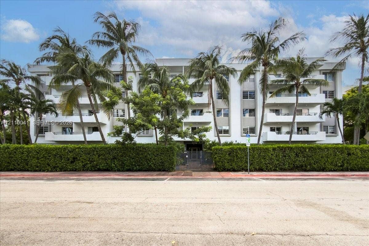 1610 Lenox Avenue, #516, Miami Beach, FL 33139 Multi-story residential building featuring private balconies, vertical architectural pillars, and mature palm tree landscaping set behind a manicured hedge