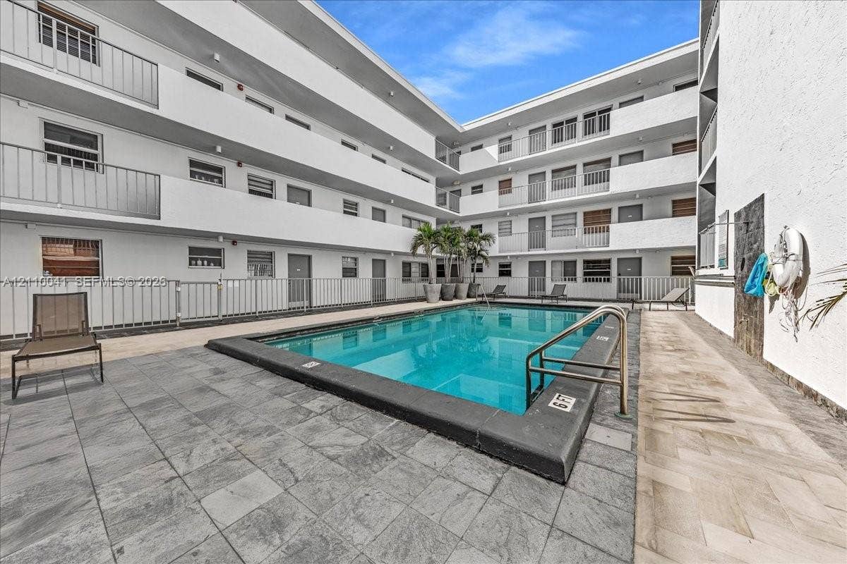 1610 Lenox Avenue, #516, Miami Beach, FL 33139 Outdoor swimming pool featuring a concrete deck, multi-level exterior balconies with metal railings, and natural stone-finish hardscaping