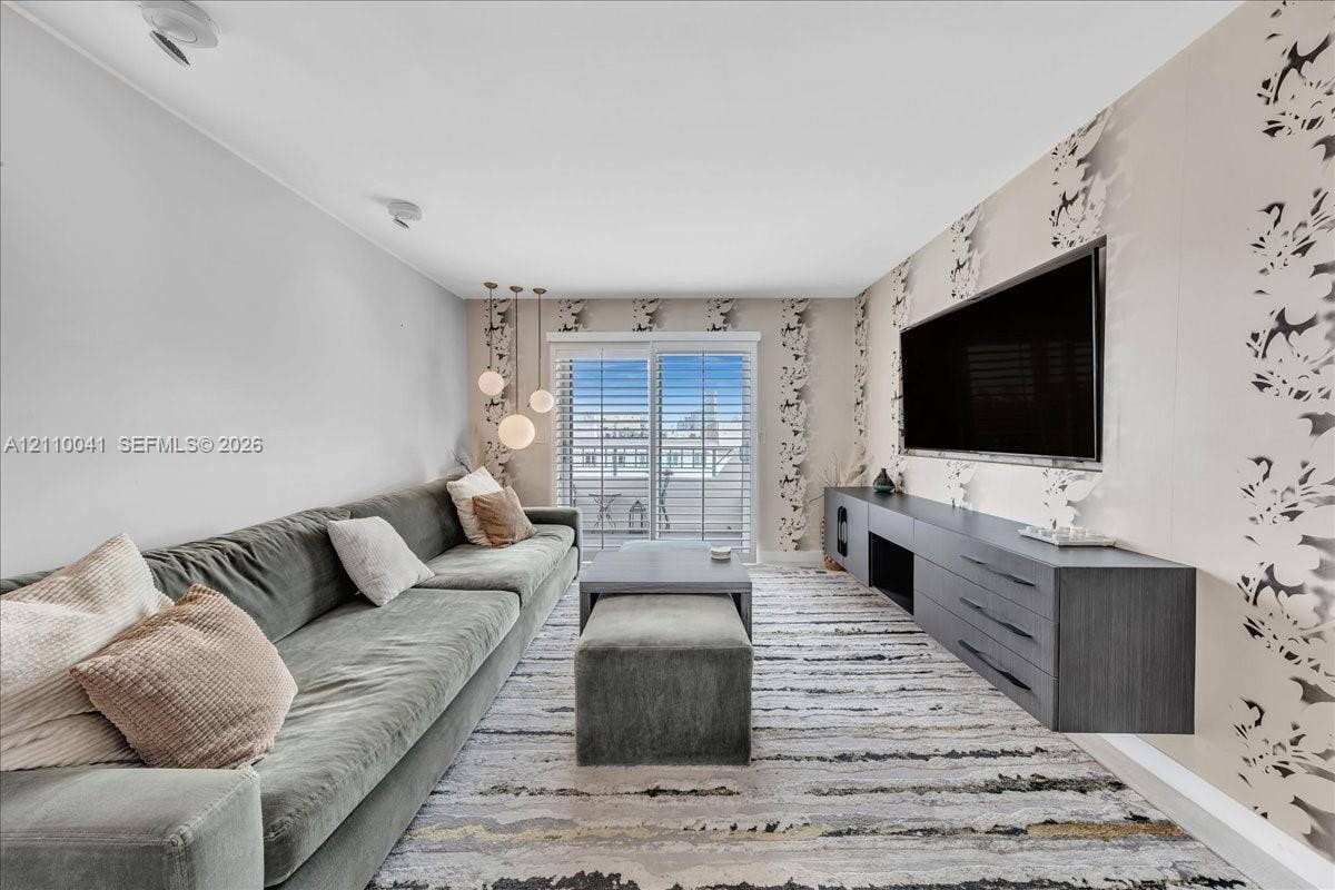 1610 Lenox Avenue, #516, Miami Beach, FL 33139 Floating charcoal-finish media console, patterned accent wallpaper, glass sliding doors with plantation shutters, and a trio of pendant lights