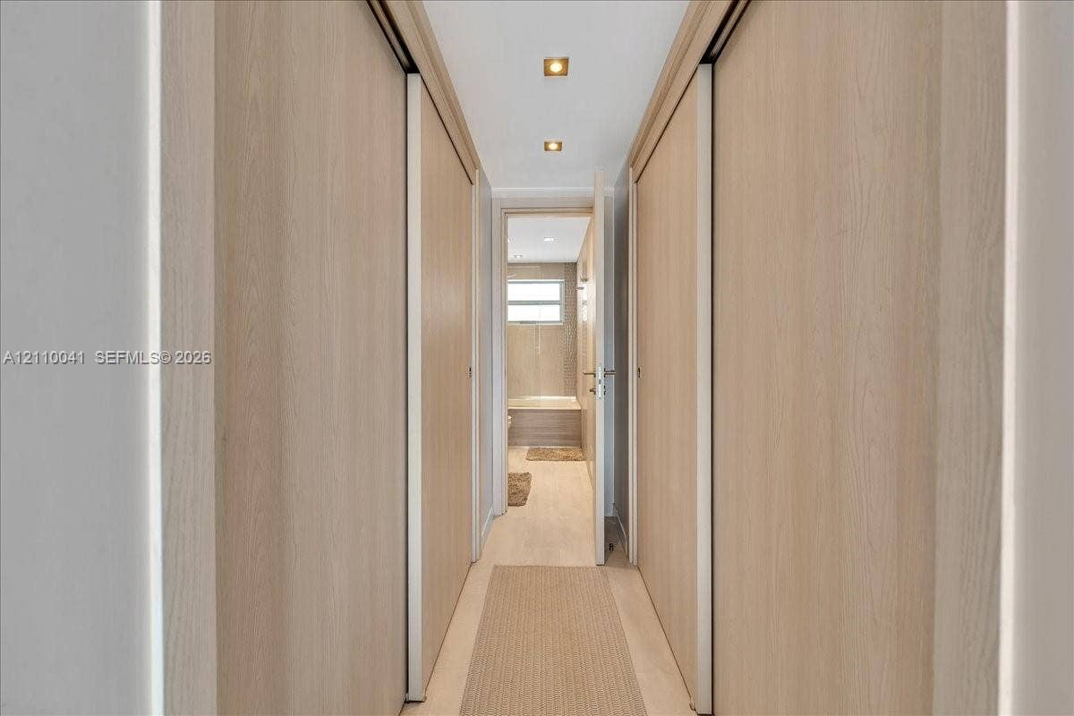 1610 Lenox Avenue, #516, Miami Beach, FL 33139 Hallway featuring floor-to-ceiling wood-finish sliding doors, recessed lighting, and wood-finish flooring