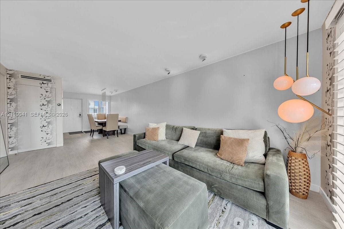 1610 Lenox Avenue, #516, Miami Beach, FL 33139 Multi-pendant brass light fixture, wood-finish flooring, patterned wallpaper accent wall, and horizontal window blinds