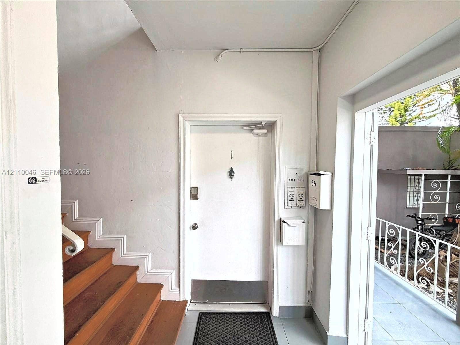Entryway featuring a solid door with a metal kick plate and viewer, wooden stairs, integrated mailboxes, and an exterior balustrade
