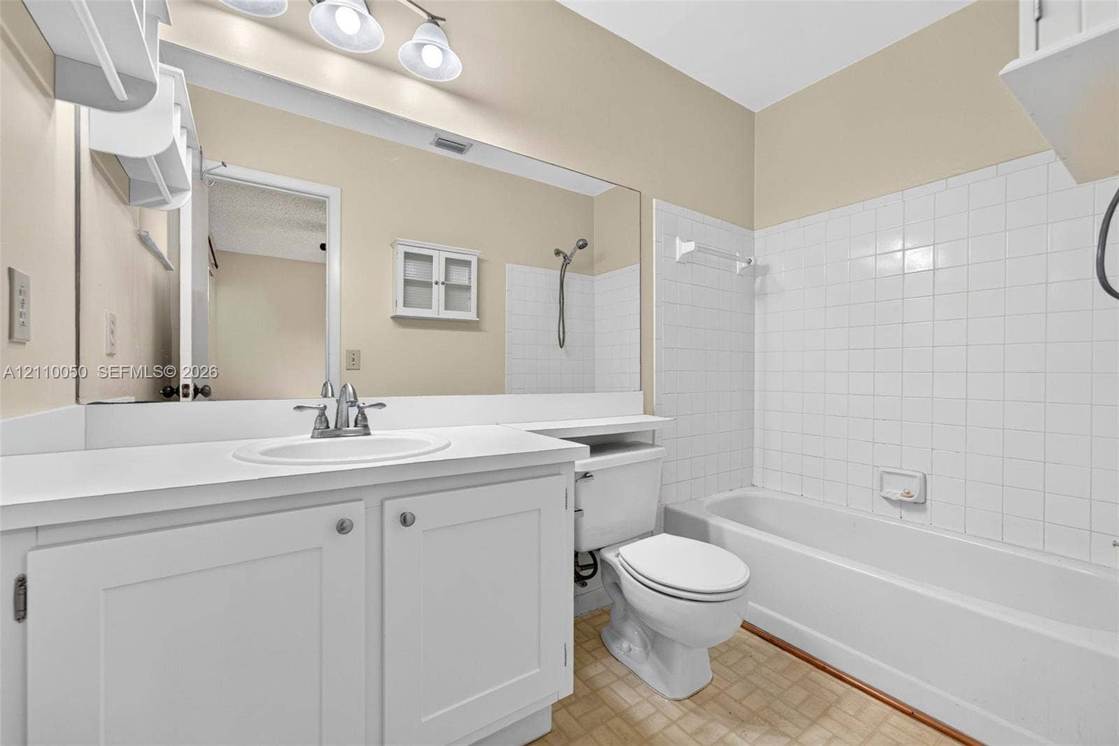 506 Westree Lane, Plantation, Plantation, FL 33324 White cabinetry with an integrated countertop, large vanity mirror, three-light fixture, and tiled tub surround