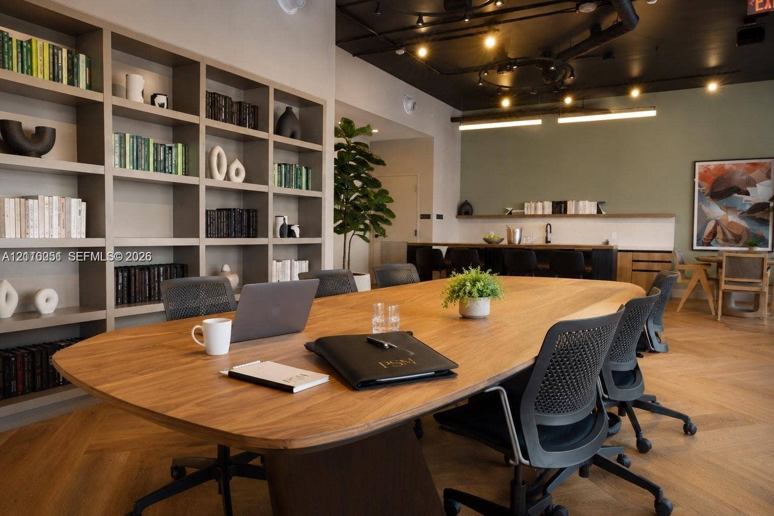 121 NE 5th Street, #1703, Miami, FL 33132 Built-in floor-to-ceiling shelving, herringbone wood-finish flooring, exposed ceiling piping, and a custom bar area with a built-in sink