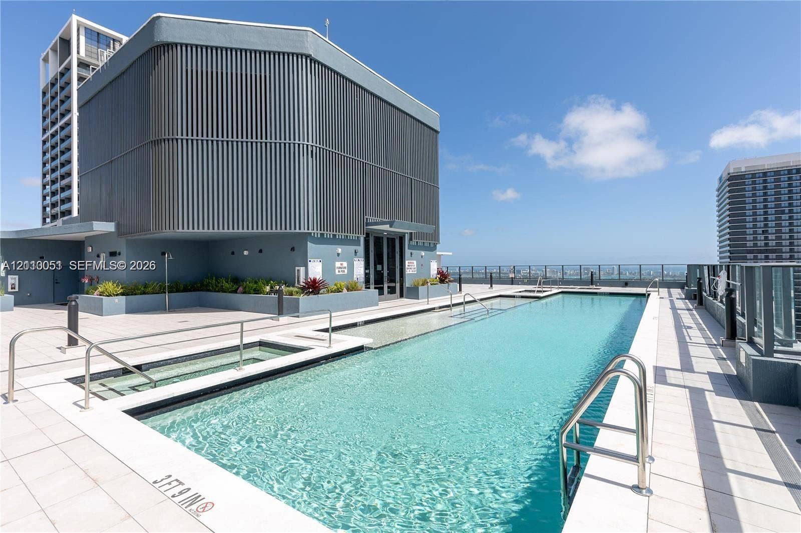 121 NE 5th Street, #1703, Miami, FL 33132 Rooftop swimming pool featuring a tiled deck, built-in hot tub, stainless steel ladders, and perimeter glass railing