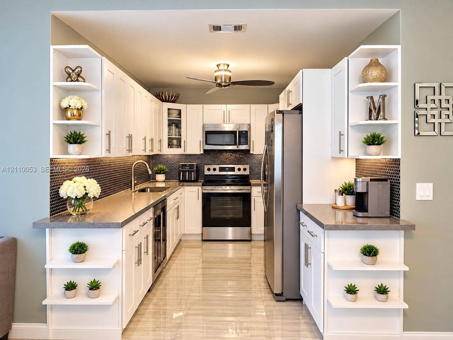 Kitchen featuring white shaker-style cabinetry, dark hexagonal tile backsplash, stone-finish countertops, stainless steel appliances, and integrated display shelving