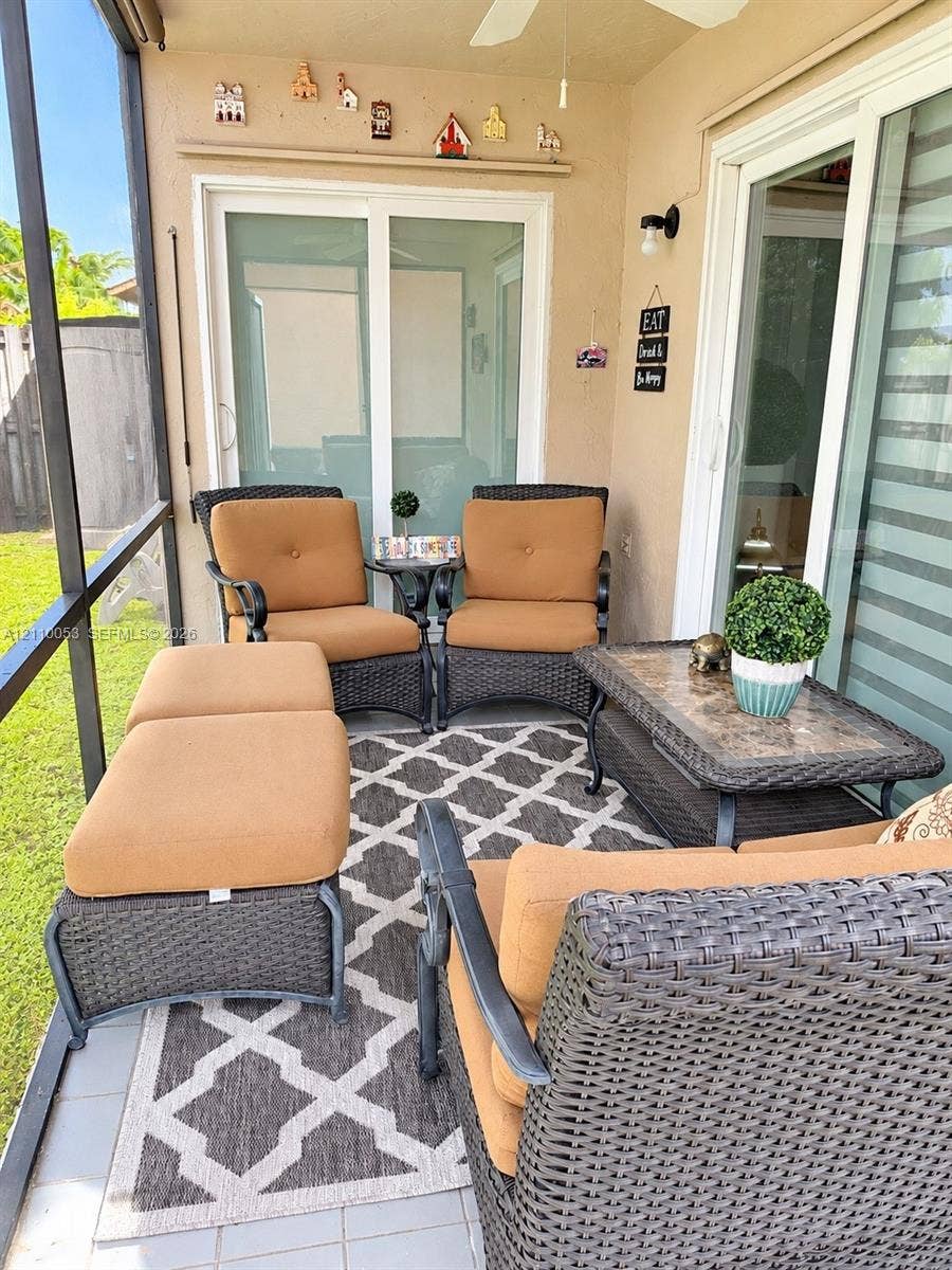 Screened-in patio featuring tile flooring, ceiling fan, and sliding glass entry doors