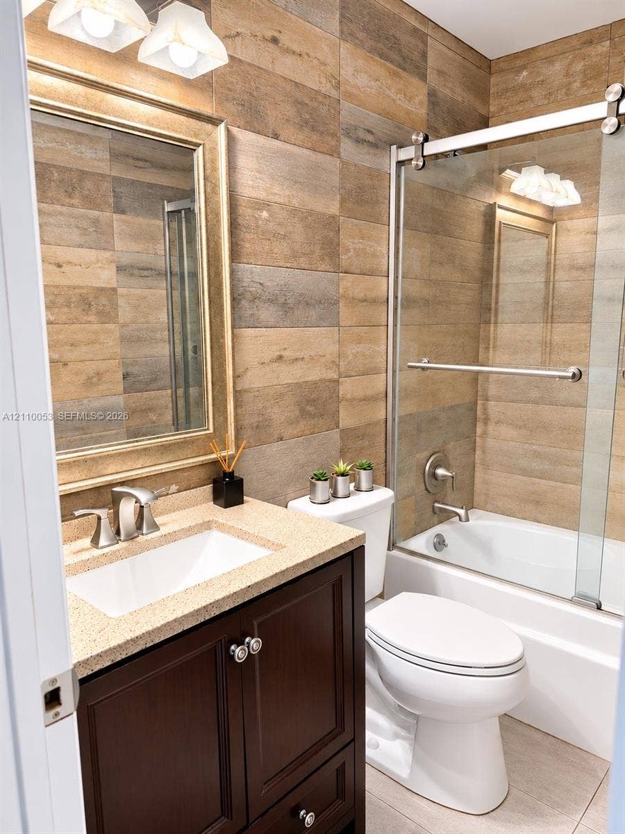 Dark wood vanity with a solid surface countertop and undermount sink, wood-finish tile wall accents, and a sliding glass shower door enclosure