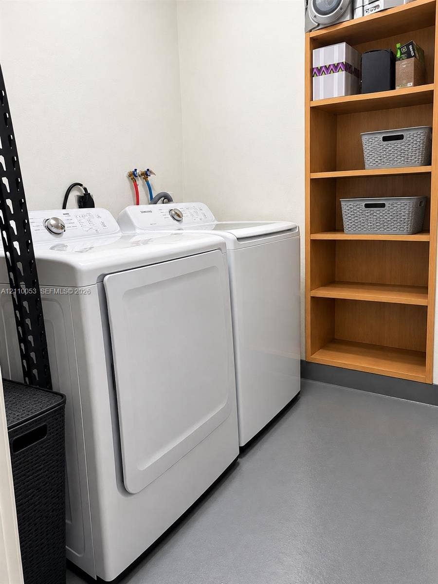Laundry area featuring built-in wood-finish shelving and solid-surface flooring