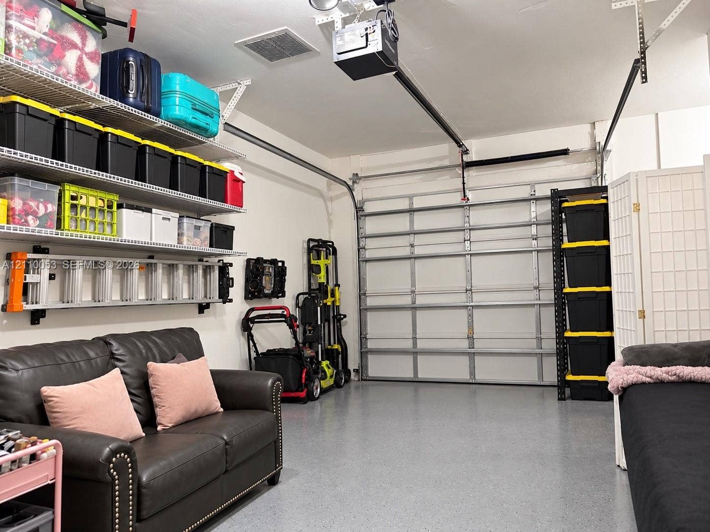 Garage featuring an epoxy-coated floor, overhead door, and wall-mounted wire shelving