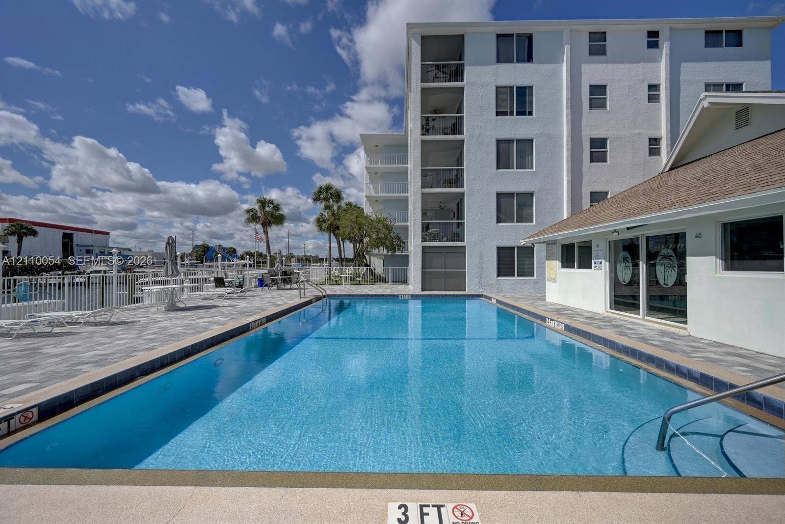 Rectangular swimming pool featuring a tiled waterline, built-in steps, and a concrete deck surround