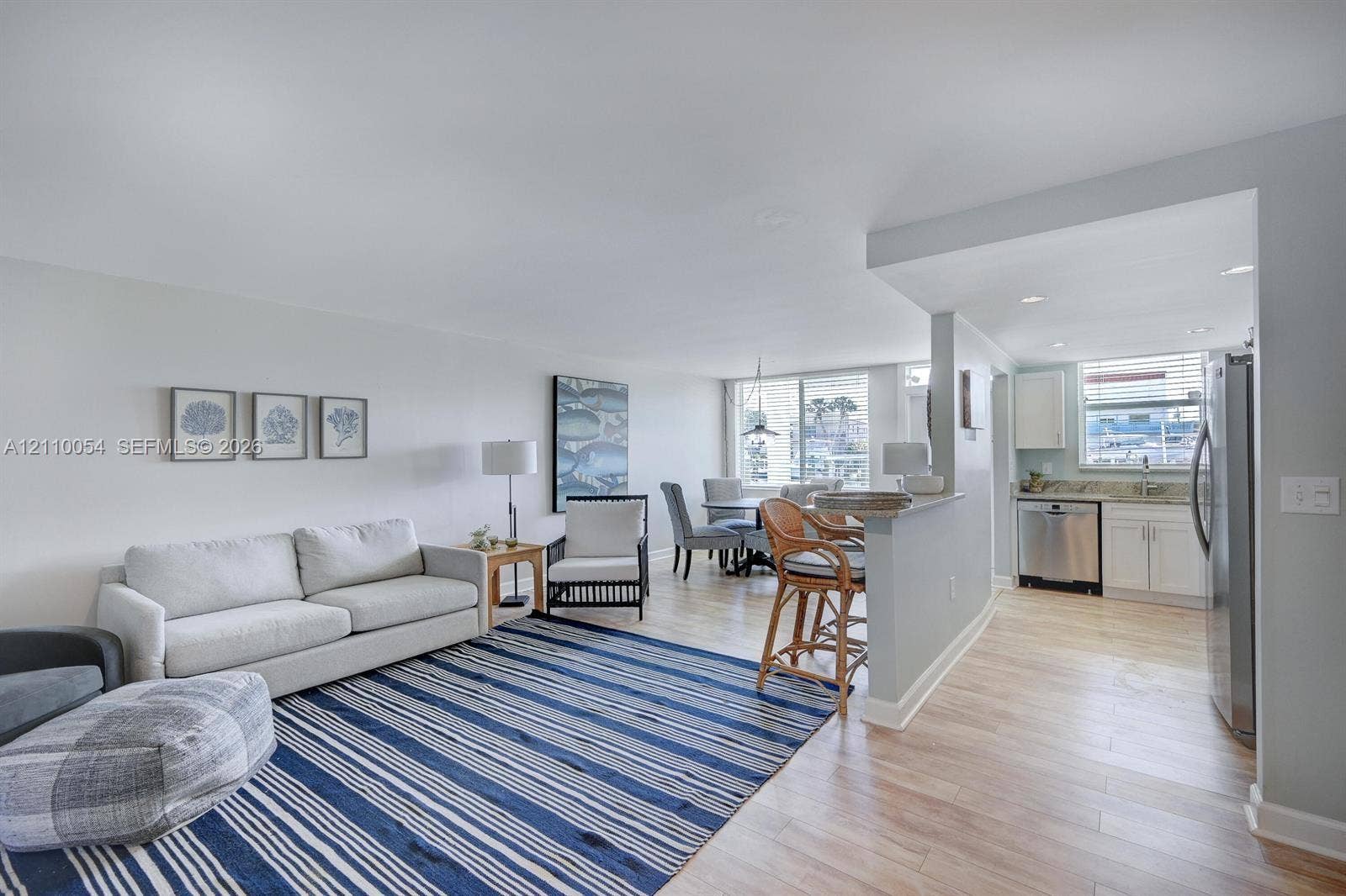 Open-concept interior featuring wood-finish flooring, a kitchen breakfast bar, recessed lighting, and white cabinetry