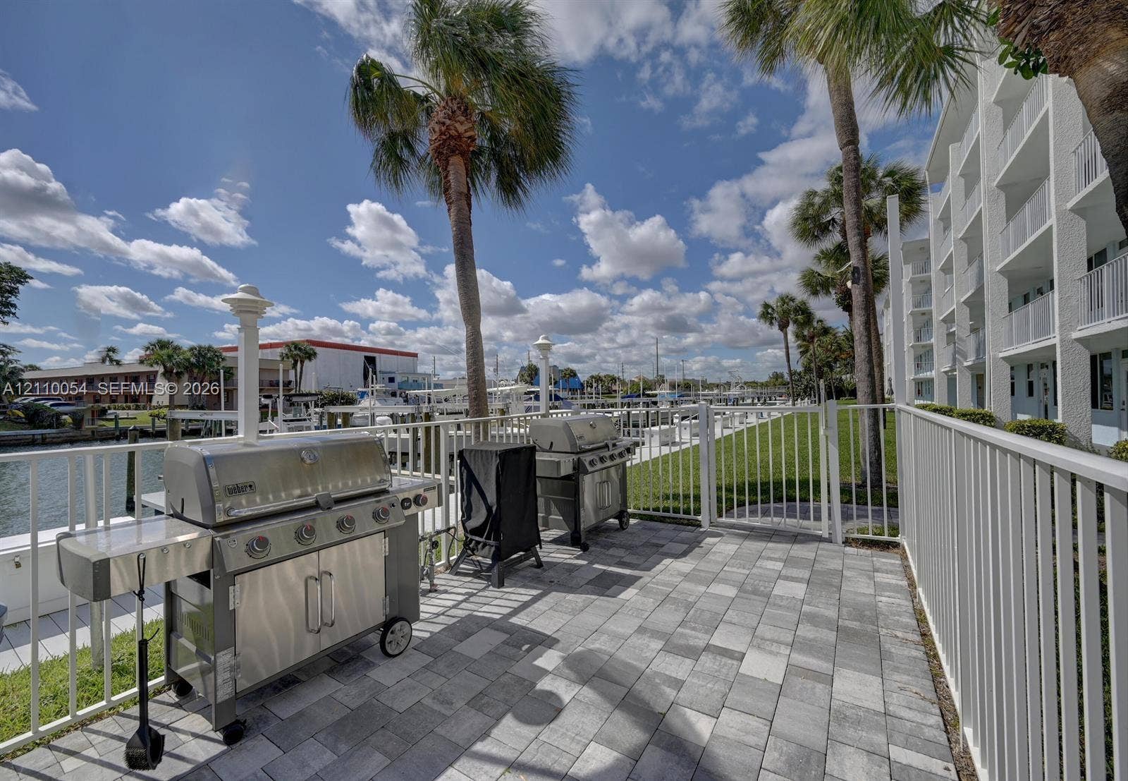 Waterfront patio featuring stone-paver flooring, metal safety fencing, and direct access to marina boat slips
