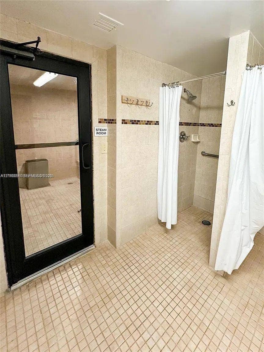 1950 S Ocean Drive, #3K, Hallandale Beach, Hallandale Beach, FL 33009 Steam room enclosed by a black-framed glass door, accompanied by a walk-in shower featuring wall-mounted hardware, tile surround, and mosaic accent tiling