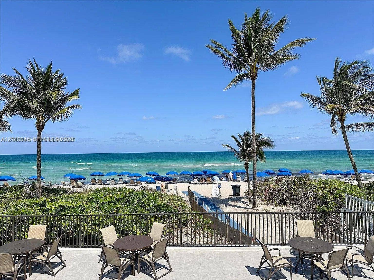 1950 S Ocean Drive, #3K, Hallandale Beach, Hallandale Beach, FL 33009 Stone-surfaced terrace featuring metal fencing, mature palm trees, and direct oceanfront positioning