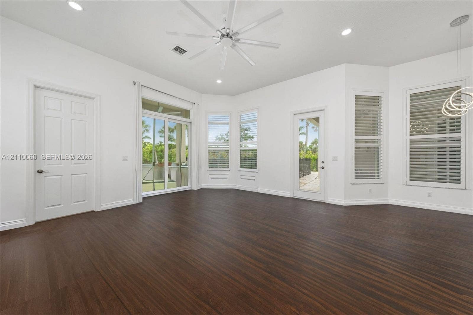 Wood-finish flooring, multi-pane windows with horizontal blinds, sliding glass door, recessed lighting, and ceiling fan